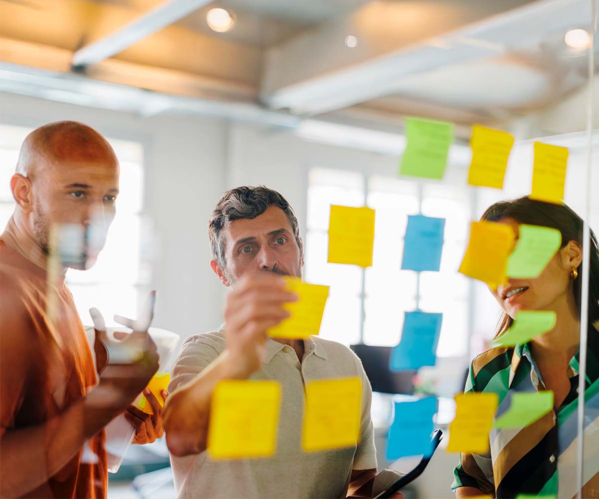 News Posting Image of 3 people in a office putting stickers on a glas surface